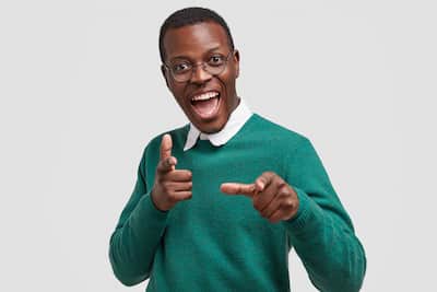 positive-overjoyed-dark-skinned-man-points-with-both-index-fingers-hints-something-wears-casual-green-jumper-smiles-broadly(1)(3)